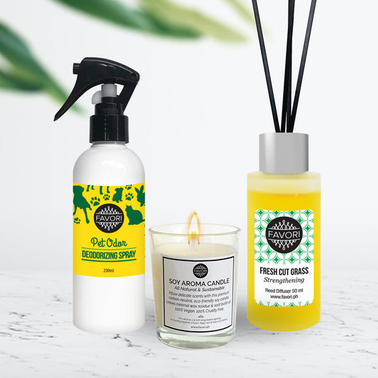 Three FAVORI Scents home fragrance products on a marble surface: an Air Spray(200ml) pet odor deodorizer, a lit Soy Aroma Candle (60g), and a Regular Reed Diffuser(50ml) fresh cut grass reed diffuser.