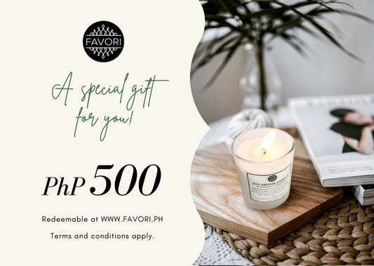 An elegant All Occasion e-Gift Card from FAVORI Scents featuring a "php 500" value, with a serene setting of a lit scented candle and an open magazine on a white table, decorated with a