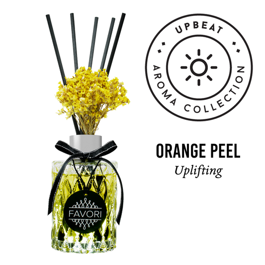 A Orange Peel Premium Reed Diffuser with yellow flowers and an "orange peel - uplifting" oil label from the upbeat aroma collection by FAVORI Scents.