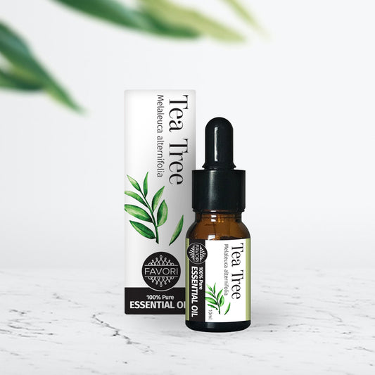 A bottle of FAVORI Scents Tea Tree Essential Oil (10ml) for aromatherapy with a dropper on a white surface against a marble background.
