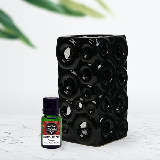 A black floral foam block next to a small bottle of FAVORI Scents Circle Ceramic Burner Device + 10ml Burner (BR) Aroma Oil on a white surface with green leaves in the background.