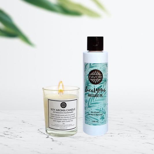 A FAVORI Scents soy aroma candle and a bottle of FAVORI Scents massage oil on a white surface with a blurred green plant in the background, creating an elegant gift package ambiance.