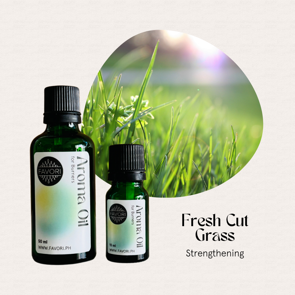 Two bottles of FAVORI Scents Burner Aroma Oils, Fresh Cut Grass, beside sunlit green grass blades.