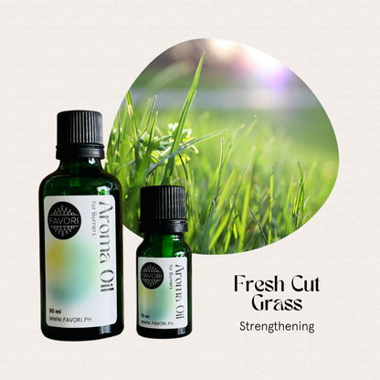 Two bottles of FAVORI Scents Burner Aroma Oils, Fresh Cut Grass, beside sunlit green grass blades.