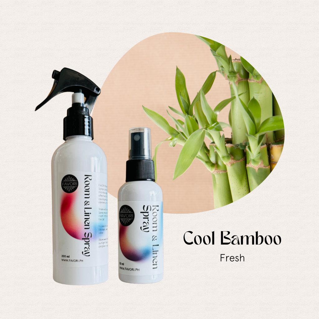 Two FAVORI Scents Regular Room & Linen Air Sprays sit beside a bamboo plant on a beige background.