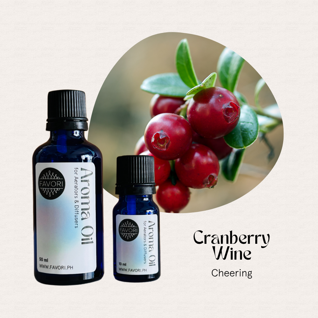 Two blue bottles of FAVORI Scents AD Aroma Oils, Cranberry Wine, Cheering, beside cranberries on a branch.