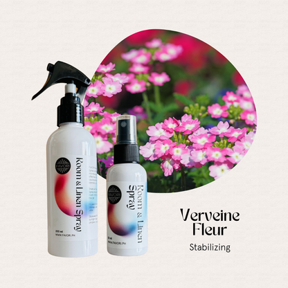 Two bottles of FAVORI Scents Regular Room & Linen Air Spray, Verveine Fleur, with pink flowers in the background.