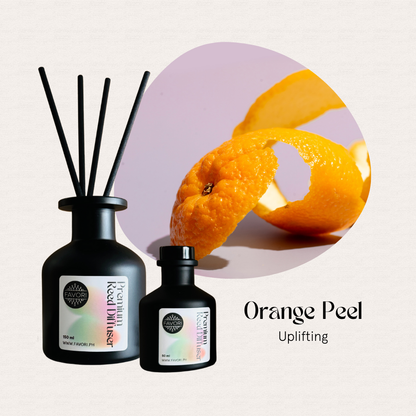 Two FAVORI Scents Orange Peel Premium Reed Diffusers with fiber sticks beside a close-up of an orange peel.