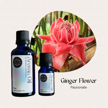 Two blue bottles of FAVORI Scents AD Aroma Oils beside a pink ginger flower with green leaves.