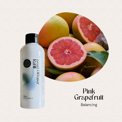 A bottle of FAVORI Scents Pink Grapefruit Reed Diffuser Refill (RDR) beside sliced grapefruit.