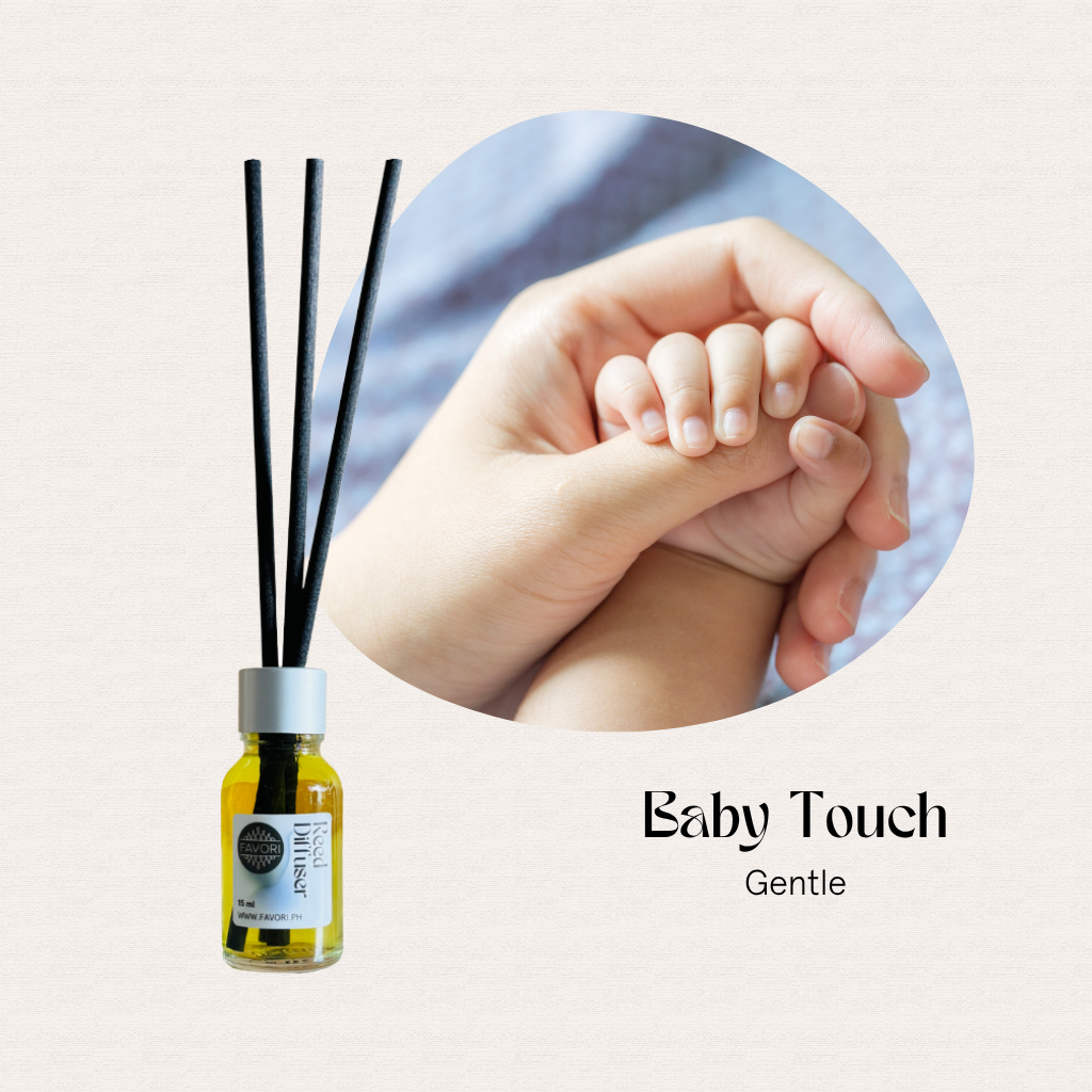 A baby grasps an adult’s finger next to a FAVORI Scents Mini Reed Diffuser labeled “Baby Touch Gentle.”.