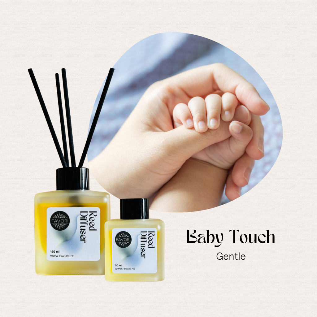 Two FAVORI Scents Baby Touch Regular Reed Diffusers with black sticks next to an adult holding a babys hand.