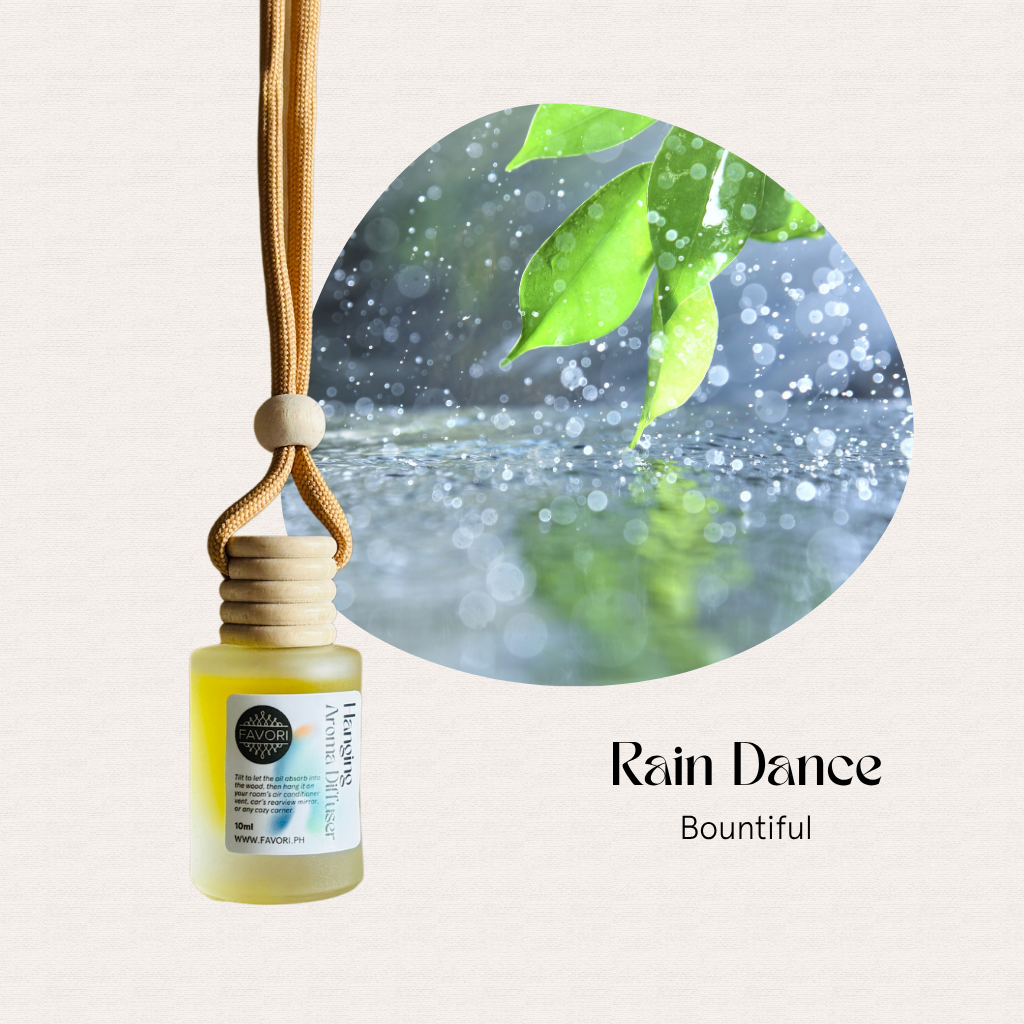 A FAVORI Scents Hanging Aroma Diffuser with a wooden cap sways as rain falls on green leaves behind.