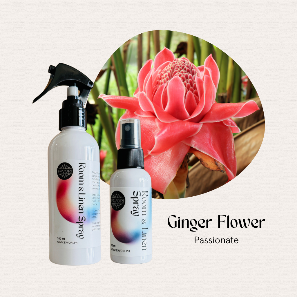Two FAVORI Scents Regular Room & Linen Air Sprays sit before a vibrant pink ginger flower.