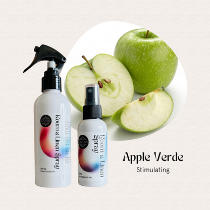 Two FAVORI Scents Regular Room & Linen Air Sprays sit beside whole and sliced green apples.