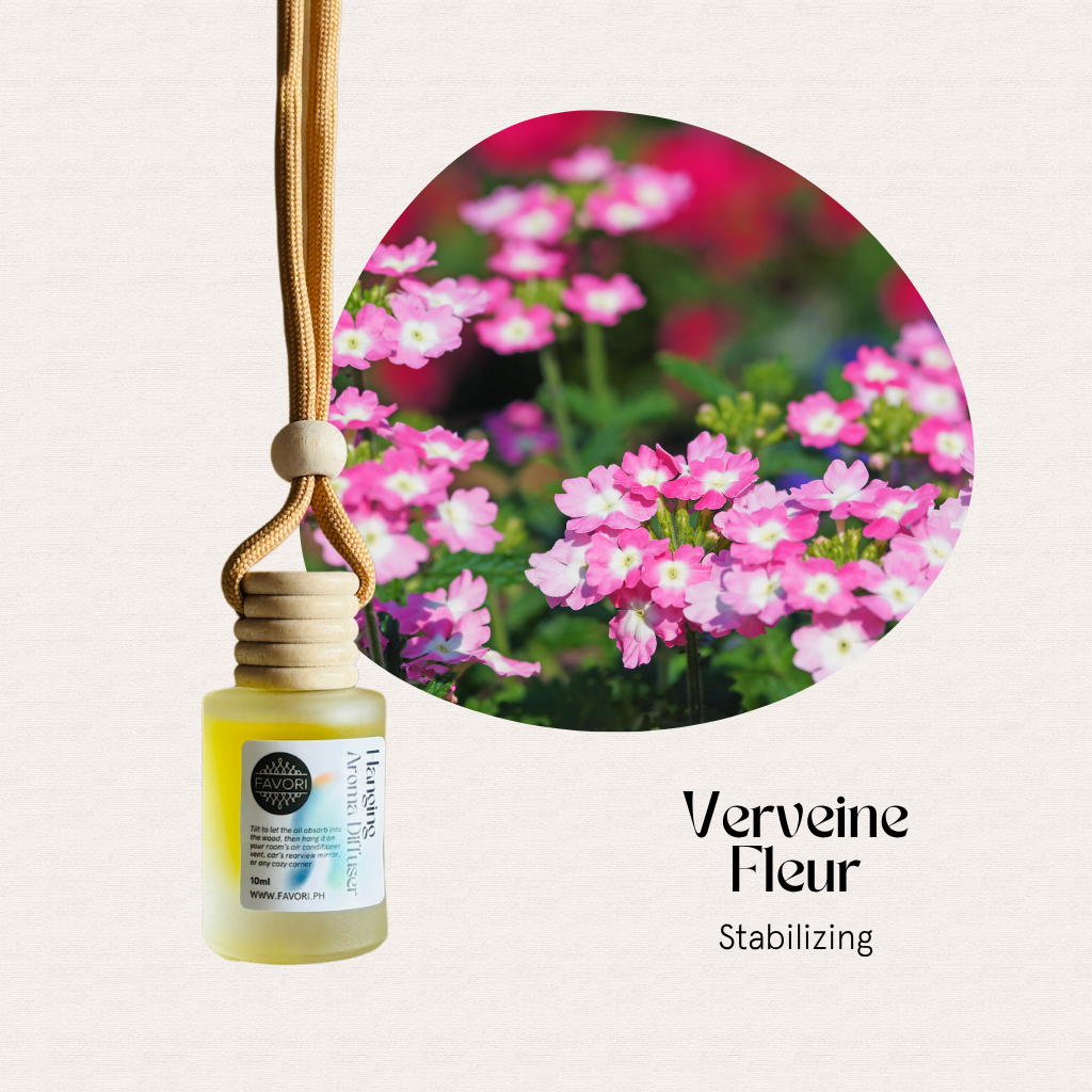 A FAVORI Scents Verveine Fleur Hanging Aroma Diffuser hangs beside pink verbena flowers.