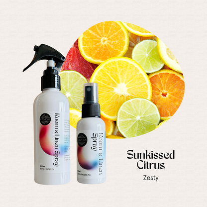 Two FAVORI Scents Regular Room & Linen Air Sprays sit by sliced citrus, evoking a Sunkissed Citrus Zesty vibe.