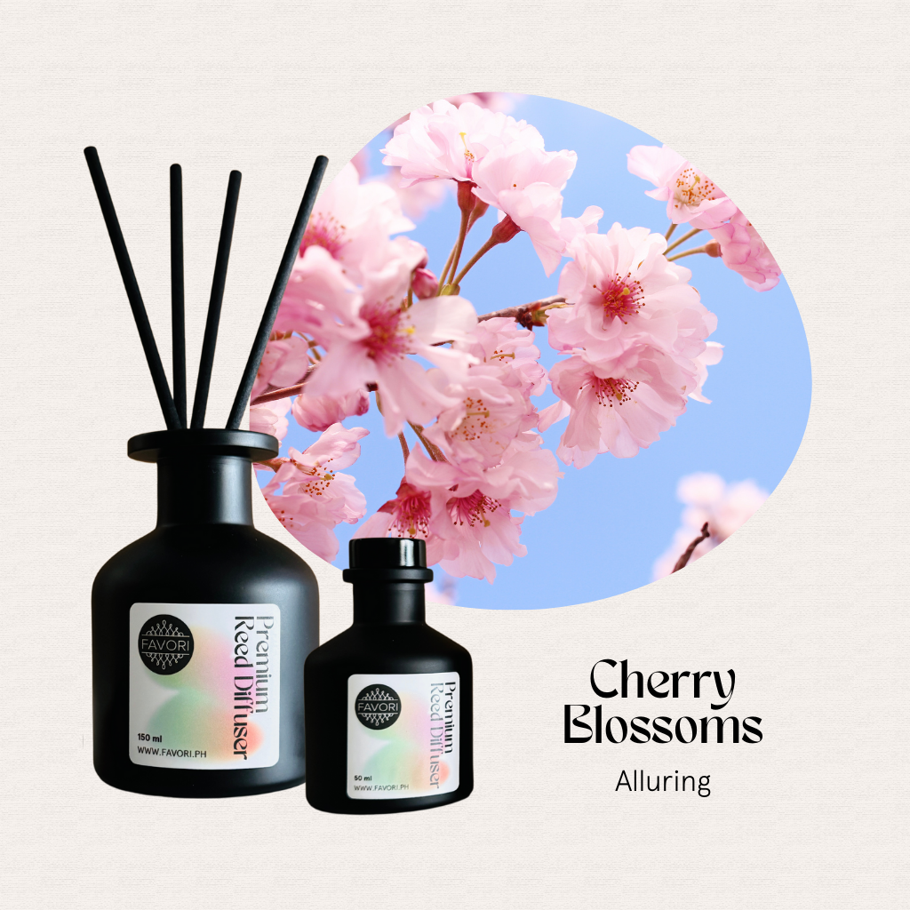 Two FAVORI Scents Cherry Blossoms Premium Reed Diffusers with sticks set against pink flowers and a blue sky.