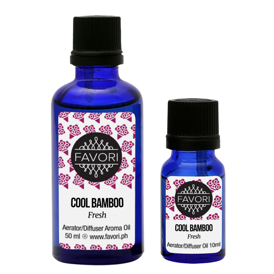 Two blue bottles labeled "FAVORI Scents Cool Bamboo Aerator/Diffuser (AD) Aroma Oil" showcase the Cool Bamboo Aroma Oil. The larger bottle holds 50 ml, while the smaller contains 10 ml. Both have black screw caps and pink floral labels on a white background, detailing their anti-microbial properties and brand logo.