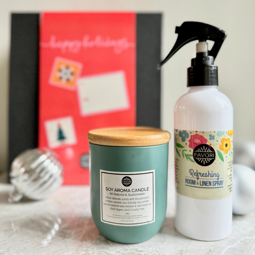 FAVORI Scents' Air Spray (200ml) and Soy Aroma Candle (160g) make a perfect pair, infusing the room with refreshing fragrances. A blurred red holiday card surrounded by small decorations can be seen in the background, enhancing the cozy and inviting atmosphere with festive ornaments.