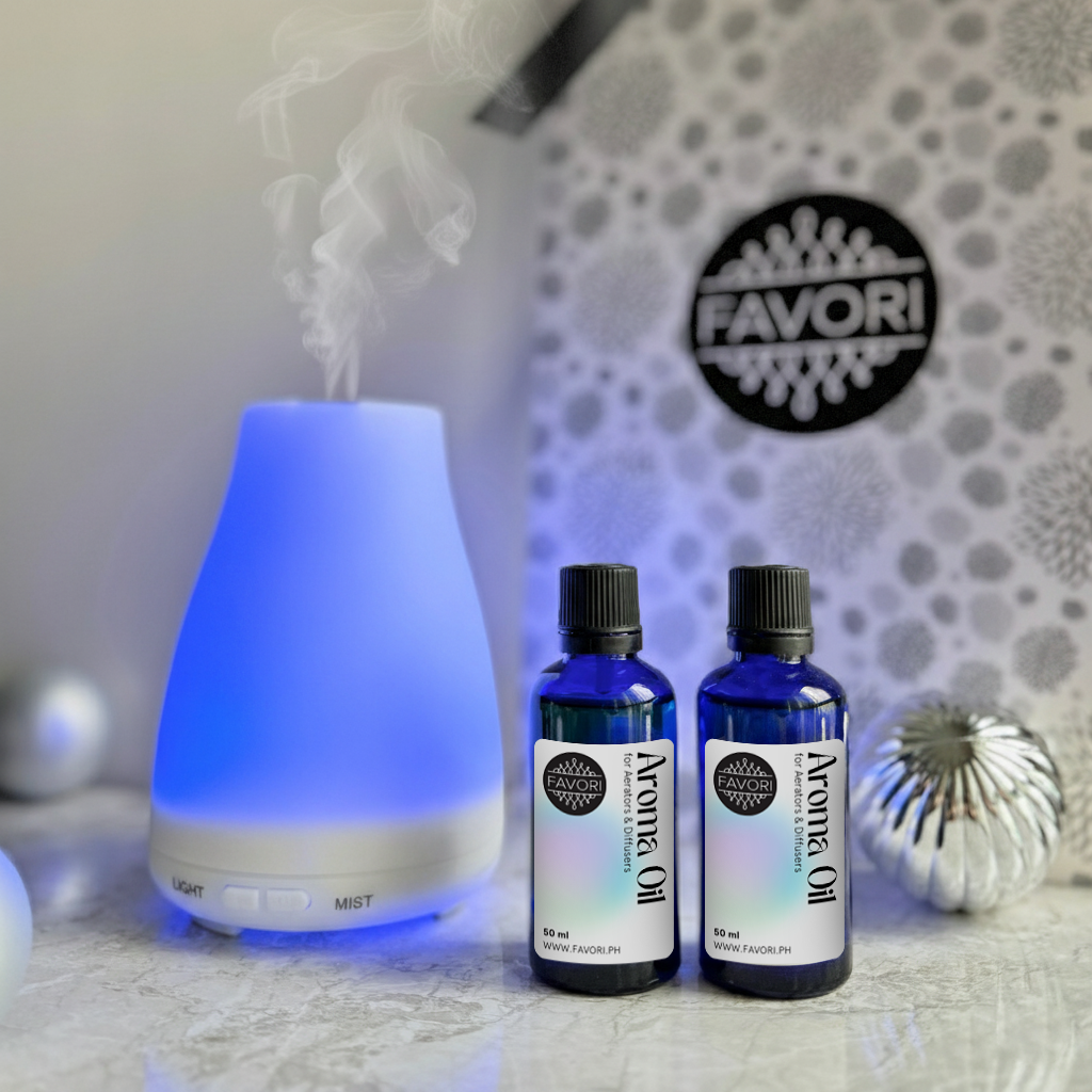 A blue-lit FAVORI Scents Vim Diffuser+Two Aroma Oils sits beside silver holiday decorations.