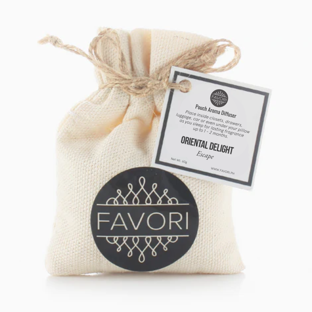 Small beige cloth pouch tied with a twine string, featuring a round black label with "FAVORI Scents" in white letters and ornamental designs. A tag attached to the string reads “Oriental Delight Pouch Aroma Diffuser (PAD).” This versatile solution offers long-lasting fragrance, with use instructions and brand information also visible.