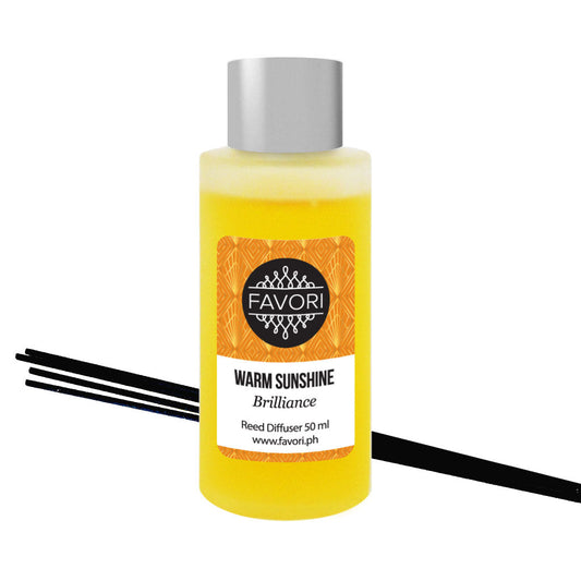 A bottle of the FAVORI Scents 'Warm Sunshine Regular Reed Diffuser' oil with black reeds.